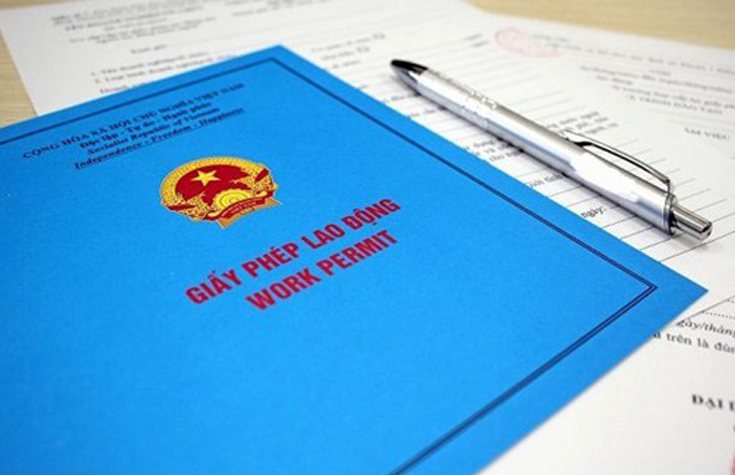 Bìa giấy phép lao động màu xanh đặt trên bàn cùng cây bút